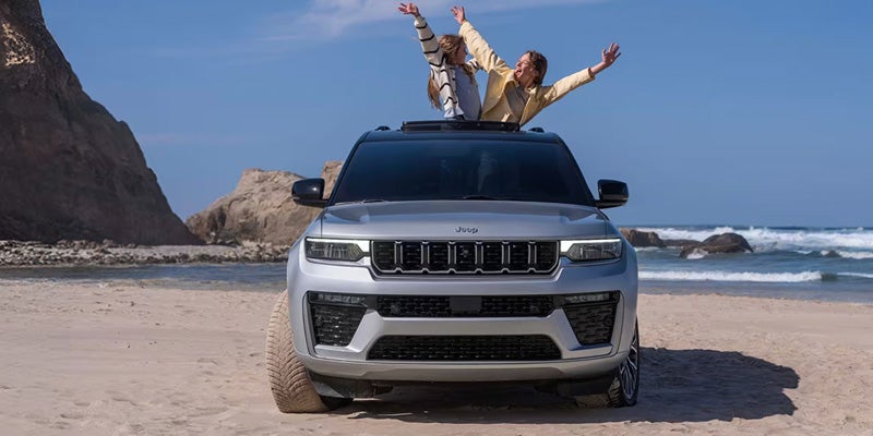 Jeep Grand Cherokee parked on beach with ocean backdrop